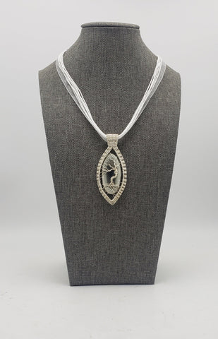 Elegant pendant necklace featuring a silver-toned oval design with a tree of life motif on a white cord.