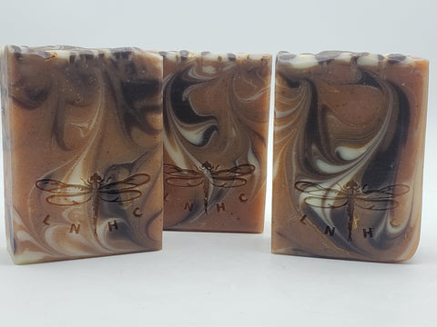 Three bars of marbled brown and white soap with dragonfly designs imprinted on them.
