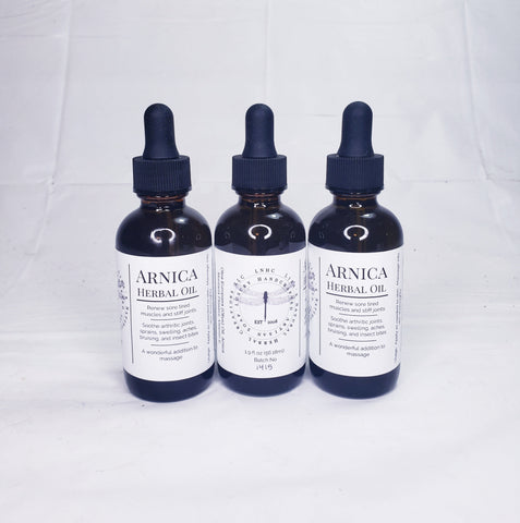 Three bottles of Arnica herbal oil with dropper caps.