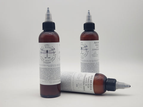 Amber glass bottles with dropper caps containing Ayurvedic hair leave in conditioner