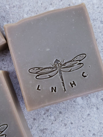 Three square bars of soap with dragonfly imprints on their surfaces.