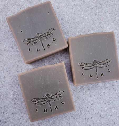 Three square bars of soap with dragonfly  imprints on their surfaces.