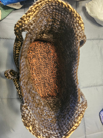 Crocheted brown tote bag with spiral shell-like decorations in lighter shades.