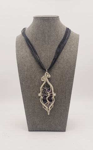 Intricate silver pendant necklace featuring a tree-of-life design within an ornate teardrop-shaped frame.