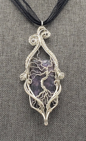 Intricate silver pendant necklace featuring a tree-of-life design within an ornate teardrop-shaped frame.