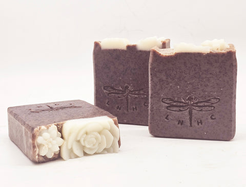 Handmade soap bars with dragonfly imprints and decorative floral designs.