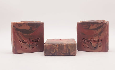 Three handmade soap bars with swirled patterns and dragonfly logos.