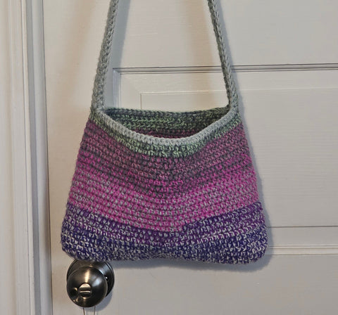 Crocheted shoulder bag with stripes in purple, pink, and gray colors.