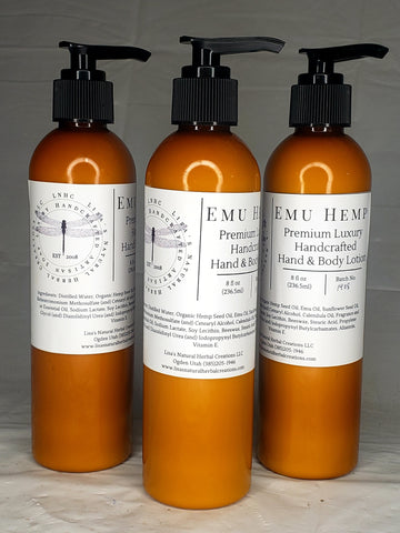 Three amber-colored bottles of EMU Hemp premium luxury hand and body lotion with pump dispensers.