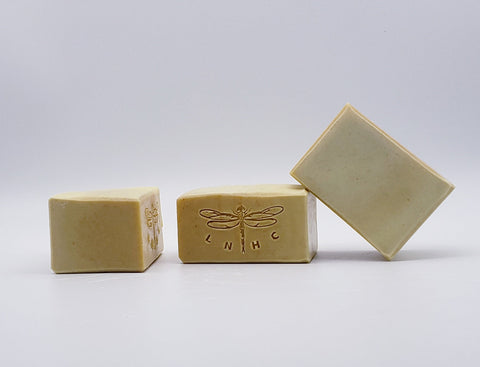Handmade soap bars with a dragonfly logo stamped on one.