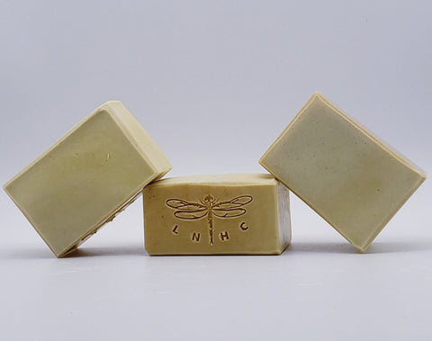 Handmade soap bars with a dragonfly logo stamped on one.